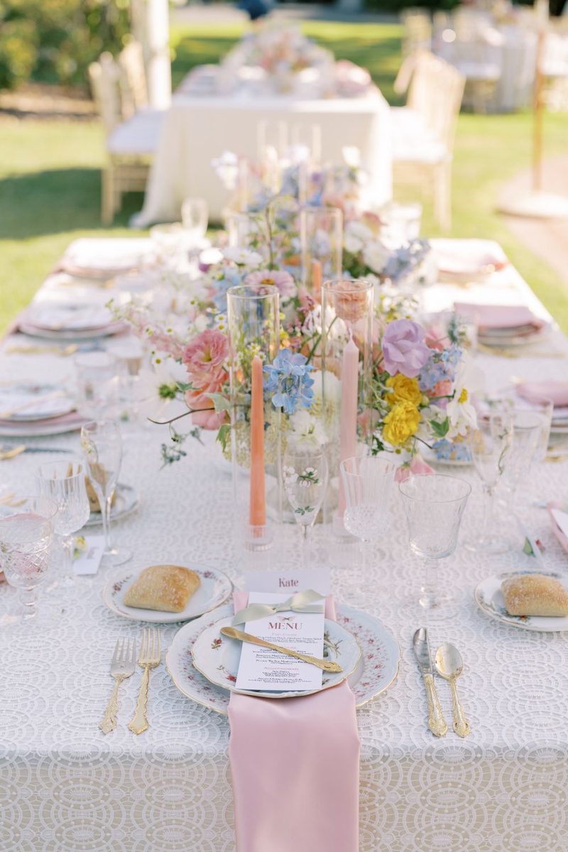 Table dressée aux tons pastel, fleurs et vaisselle claire.