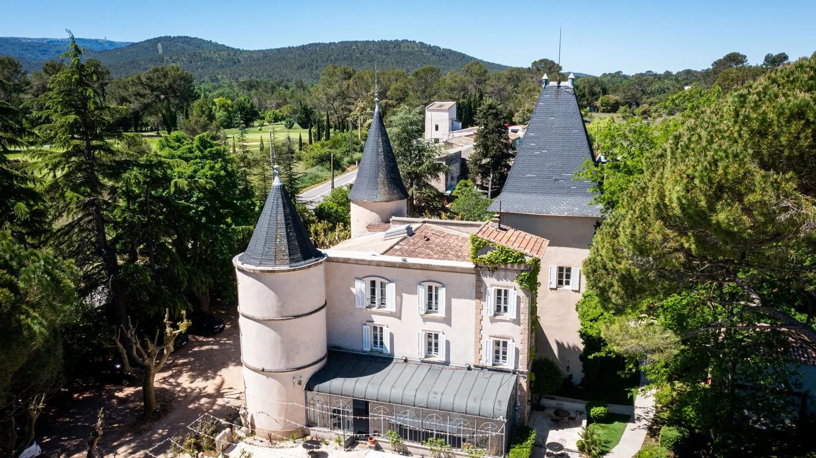 Vue aérienne du Château de Nans, ses tours et le parc boisé.
